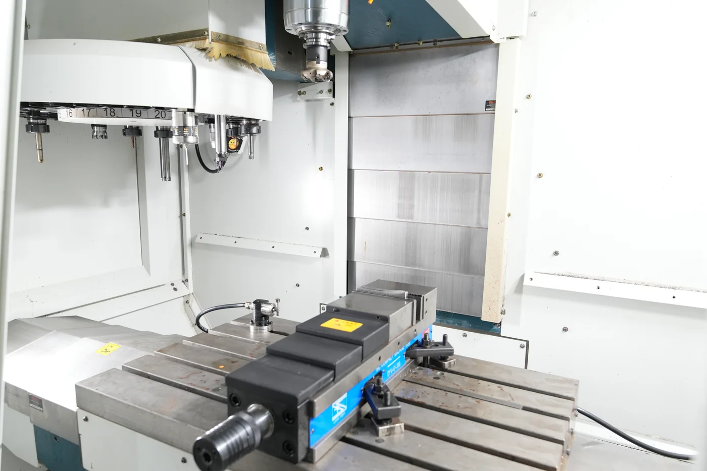 Interior do centro de usinagem CNC com mesa, spindle e magazine de ferramentas